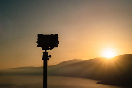A travel image of a camera shooting sunrise on top of a hill In the distance, amazing sunrise and...