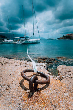 Mooring rope and bollard on sea water and yacht at the background. Dramatic Rainy clouds above mediterranean seaの写真素材