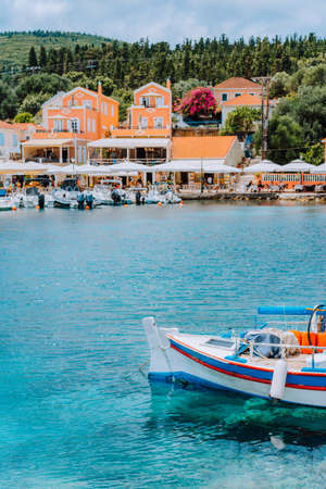 Traditional colorful Greek fishing boat in front of picturesque village, Greeceの写真素材