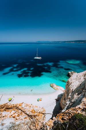 Fteri beach, Cephalonia Kefalonia, Greece. White catamaran yacht in clear blue sea water. Tourists on sandy beach near azure lagoonの写真素材