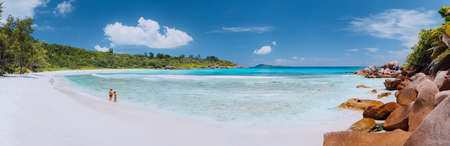 Panoramic shot of wide picturesque white sand beach, Seychelles, La Digue, Anse Cocos. Couple enyoing vocation time conceptの写真素材