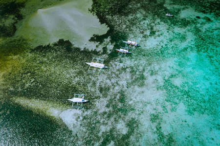 Aerial drone top down view of local banca boats and coral reef in shallow transparent lagoon water El Nido. Bacuit archipelago. Palawan, Philippinesの写真素材