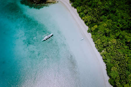 Aerial drone view of the beautiful paradise lagoon and white sand beach. Local boats on the surface....