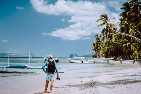 Back view of the man photographer with camera on pristine beach. Travelling tour most beautiful...