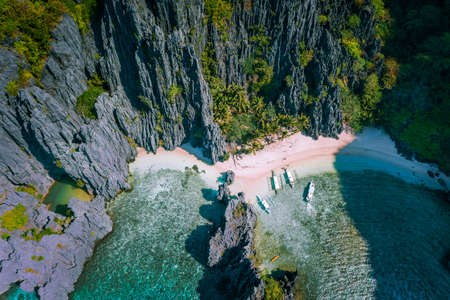 El Nido, Palawan, Philippines. Aerial view of Secret hidden lagoon beach with tourist banca boats on island hopping tour surrounded by karst cliffs sceneryの写真素材