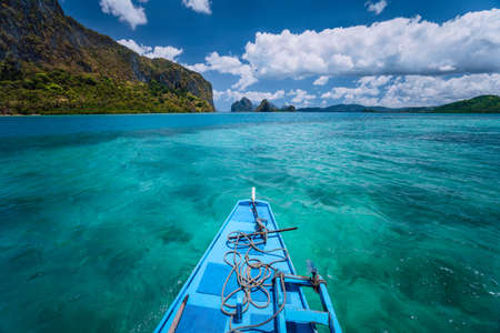 Island hopping Tour boat hover over open blue ocean water between exotic karst limestone islands on...