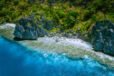 Aerial view of beautiful tropical limestone rocks, blue ocean and coral reef edge at El Nido,...