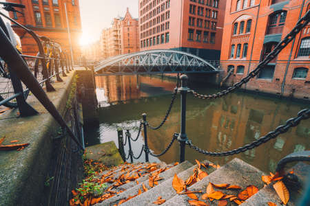 Speicherstadt warehouse district in Hamburg, Germany. Old brick buildings and channel of Hafencity quarter on autumn evening with sunset golden flaresの写真素材
