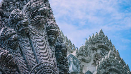 Skulptur of many snake heads. Shape of ancient stone temple in backgroundの写真素材