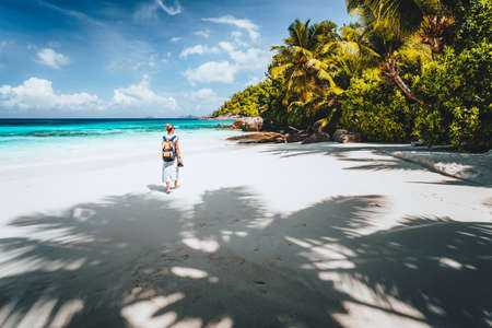 Female tourist enjoy empty tropical beach on vacation. White sand beach, palm trees and blue ocean lagoon. Exotic paradise recreation vacation conceptの写真素材