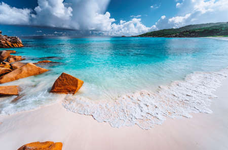 Gentle foam wave on Grand Anse beach, La Digue, Seychelles. White clouds, crystal clear ocean...