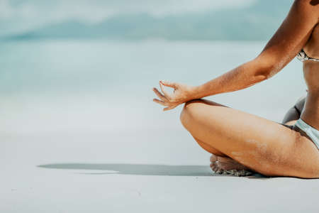 Crop of female hands and legs meditating activity on the beachの写真素材