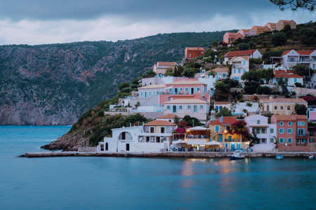 Assos town in evening twilight. Vivid colorful local house buildings at hill. Kefalonia, Greece.の写真素材