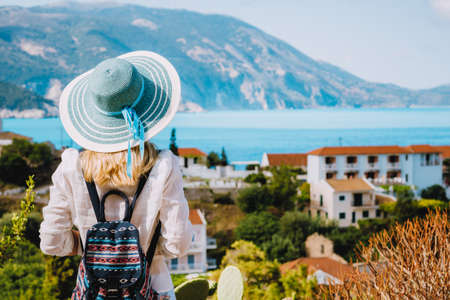 Tourist female with blue sun hat enjoying greek cute and vivid colored Assos town on Kefalonia island, Greece.の写真素材