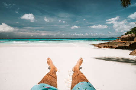 Tropical vacation. Man lying and enjoying on a sandy tropical beach, ocean and blue skyの写真素材