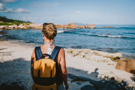 La Digue Island, Seychelles. Adult women with backpack enjoying beautiful tropical secluded beach in evening lightの写真素材