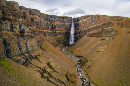 Aerial view of Hengifoss waterfall in East Iceland. Hengifoss is the third highest waterfall in Iceland and is surrounded by basaltic strata with red layers of clay between the basaltic layersの写真素材