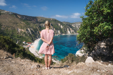 Young woman on Petani beach Kefalonia, admiring highly excited picturesque panorama of emerald blue bay of Mediterranean sea and steep coastline hills. Greeceの写真素材