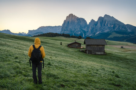 Man hiker enjoying sunrise at Alpe di Siusi, Dolomites mountains, Italy