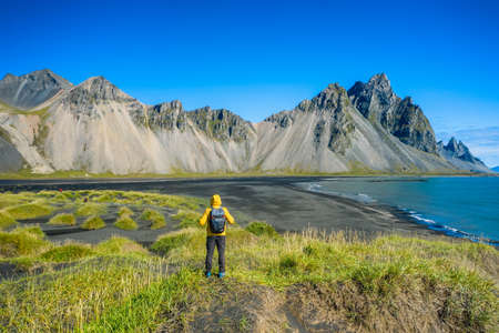 Man hiker with backpack at black sand dunes on the Stokksnes headland on southeastern Icelandic...