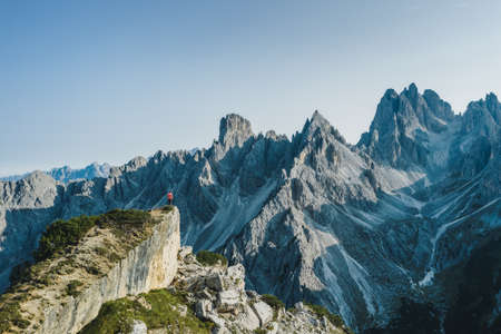 Aerial view of a man on cliff edge admiring epic Cadini di Misurina mountain peaks, Italian Alps, Dolomites, Italy, Europe.の写真素材