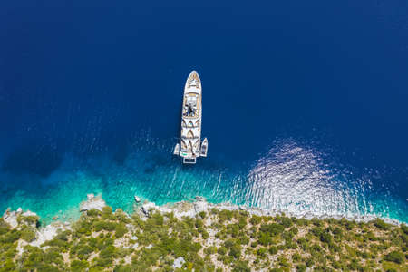 Aerial top down view of luxury lonely yacht boat in turquoise blue sea on secluded remote coast of Kefalonia Ionian island, Greeceの写真素材