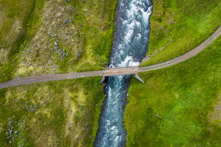 Iceland. Aerial view of road and small bridge over blue mountain river. Aerial scenic view of Iceland landscape. Travel vacation conceptの写真素材