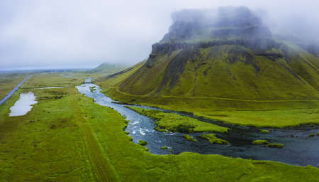 Iceland. Aerial view on mountain, field and river. Landscape in Iceland at the day time. View from drone. Summer. Cloudy weather. Fresh grass on field. Travel and vacation imageの写真素材