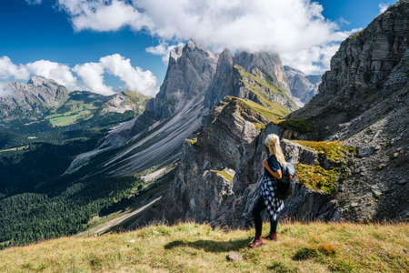 Adult women with backpack enjoy landscape of Seceda peak in Dolomites Alps, Odle mountain range, South Tyrol, Italy, Europe. Travel vacation conceptの写真素材