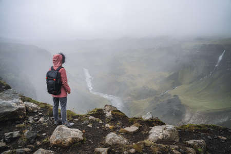 Close up of a woman with backpack enjoying icelandic highland and river fossa close to Haifoss waterfall in Icelandの写真素材