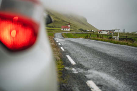 Car stoped on the road with view of typical rural Icelandic Church with red roof in Vik region. Icelandの写真素材