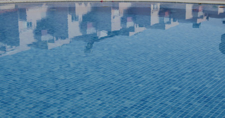 Empty swimming pool with blue clean water. Reflection of buildings in swimming pool. Sunny day. Nobodyの写真素材