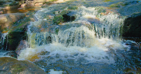 Close-up of mountain fast river waterfall on a sunny summer day. Nature cascade landscape. Forest in...