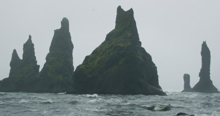 The black sand beach of Reynisfjara with waves hitting the shore on foggy rainy stormy day Vik, Icelandの写真素材