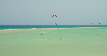Kiters and surfers cut the waves of Atlantic ocean on the coast of Canary Islands. Extreme sports in Playa de Sotavento de Jandia, Fuerteventura, Spain.の写真素材