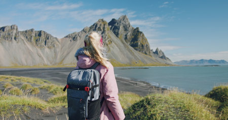 Morning scene of female traveler exploring Stokksnes cape with Vestrahorn in background Sunny summer day in Icelandの写真素材