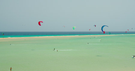 Kiters and surfers cut the waves of Atlantic ocean on the coast of Canary Islands. Extreme sports in Playa de Sotavento de Jandia, Fuerteventura, Spain.の写真素材