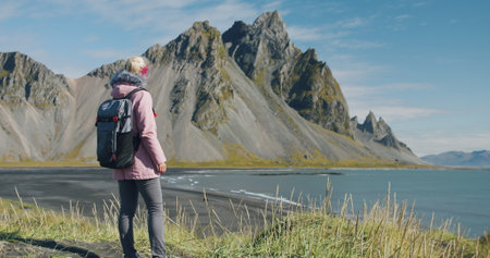 Morning scene of female traveler exploring Stokksnes cape with Vestrahorn in background Sunny summer day in Icelandの写真素材