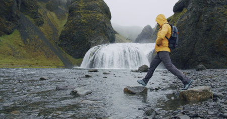 Man with backpack cross the river of Stjornarfoss waterfall near Kirkjubaejarklaustur at Icelandの写真素材