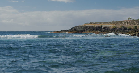 Splashing waves. Black rocky volcanic beach with black lava stones. Puerto de la Santiago, Tenerife. Punta Blanca or Punta Juanita - best place to surf or chill relax. Coast of the Atlantic Ocean.の写真素材
