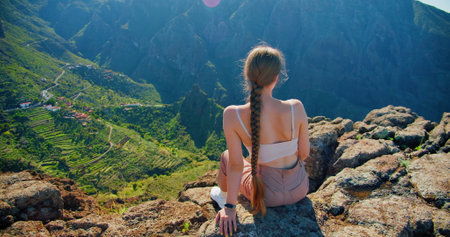 Masca Gorge, Tenerife. Middle aged woman sitting on viewpoint admiring view of Masca village. Beautiful scenery landscape on sunny day.の写真素材