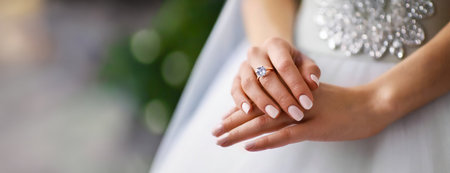 Bride's Hand with a Diamond Ring, Blurred Wedding Decoration. The focus is on a bride's hand adorned with a new diamond ring, with wedding decorations blurred in the background.の素材