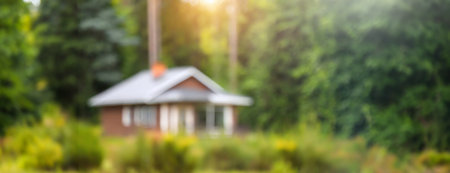 A blurred view of a small house surrounded by lush greenery and trees, creating a sense of seclusion and tranquility in a rural setting..の素材
