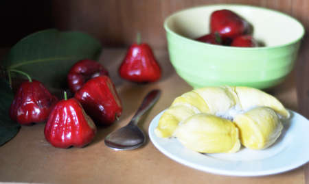 red guava fruit and durian fruit flesh with green leaves on a wooden table