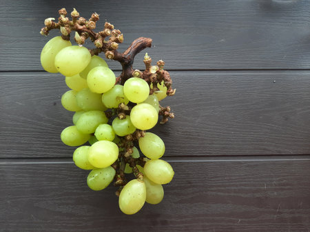 bunch of  Green Grapes on pedestal black table and wooden background with space for your writing