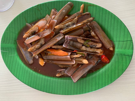 Stir-fried clams with chili sauce on a green plateの写真素材