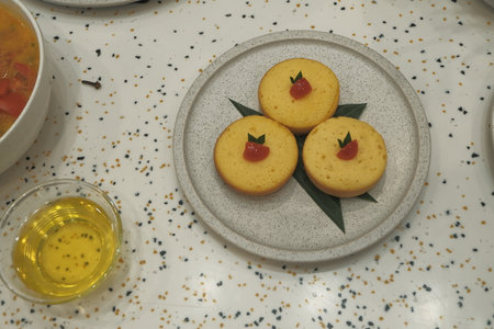 Cupcakes with red fruit on a plate with a cup of tea
