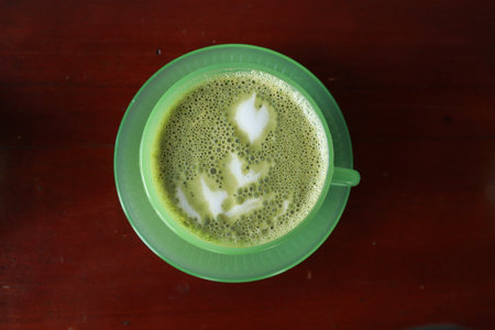 Green tea latte art on wood table background. Top view.