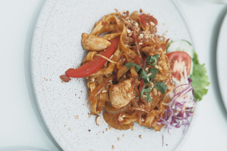 Chicken and vegetables on a white plate in a restaurantの写真素材