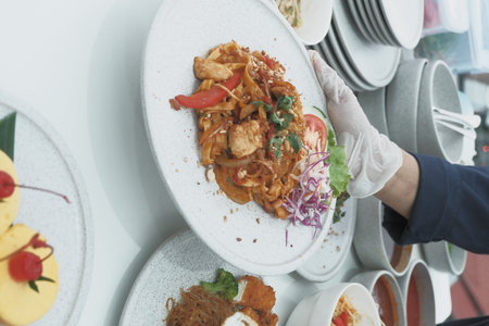 Close up of Asian woman hand holding a plate with Thai food.の写真素材